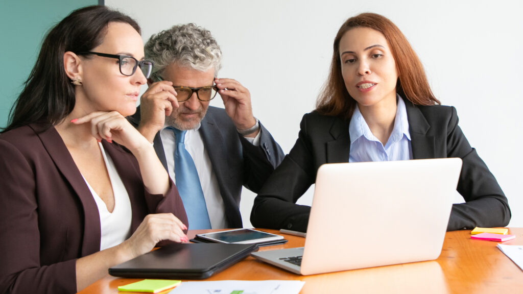 Decision-makers look at a laptop screen displaying compelling proof for investing in new technology.