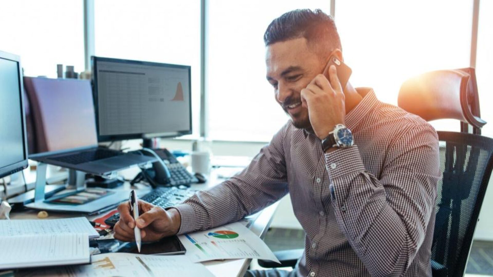 A B2B seller works on revenue forecasting while sitting at his desk on a phone call.