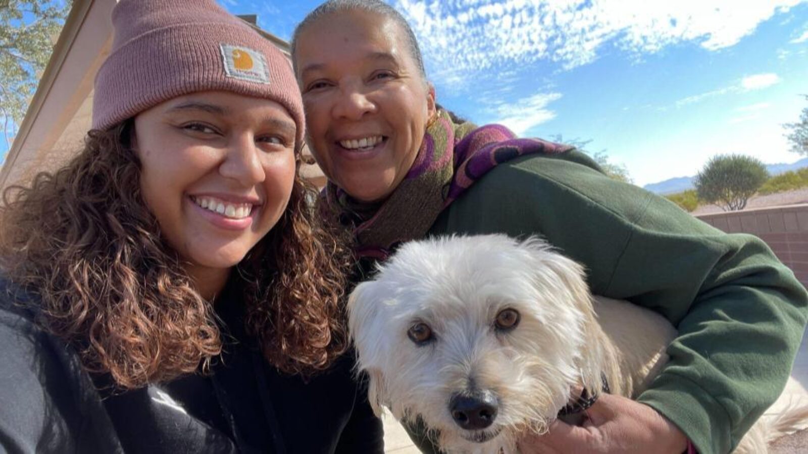 Two women smiling with a dog